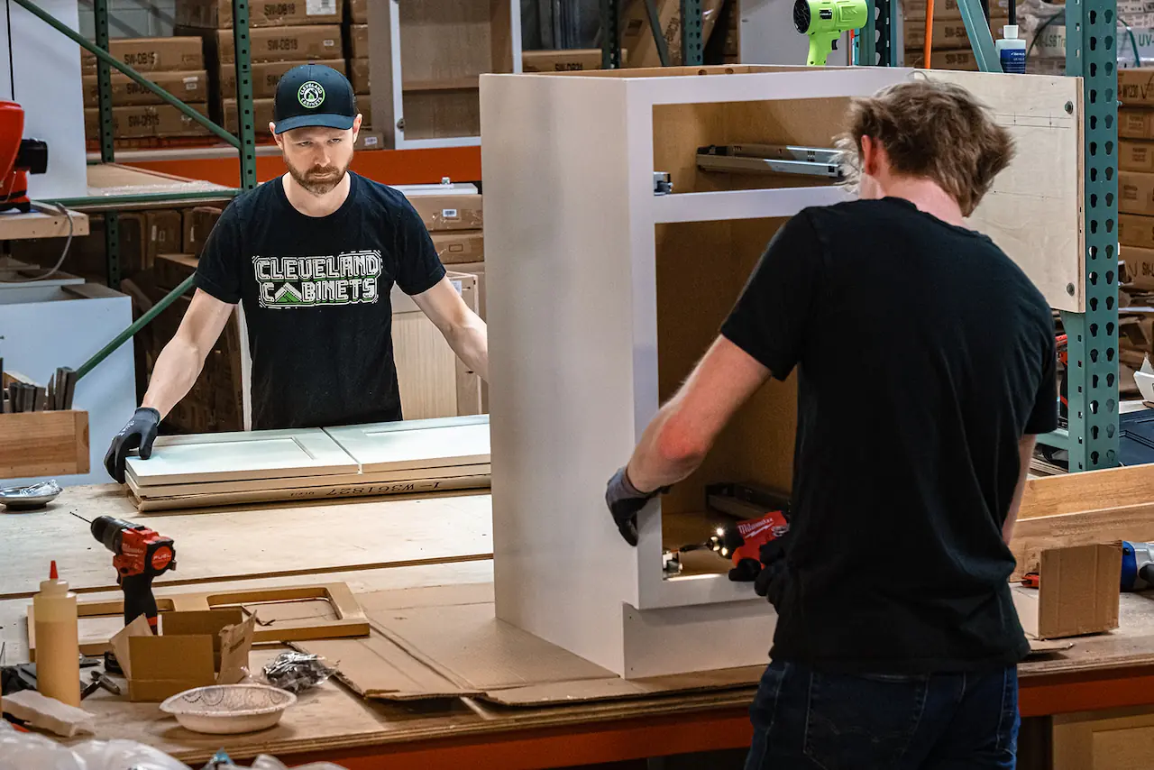 Workers assembling white cabinet in the shop for Parma Ohio