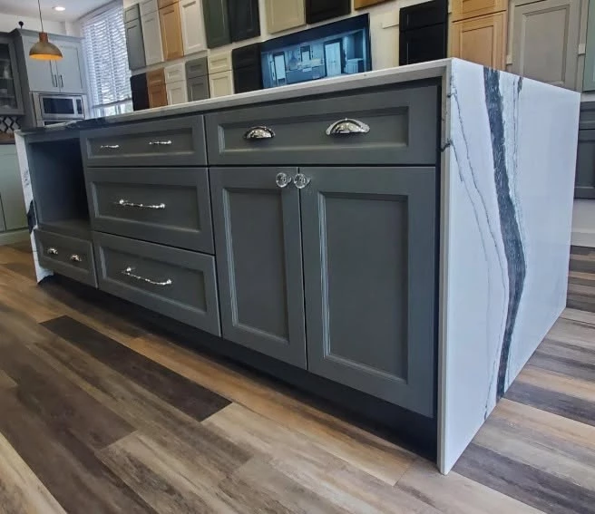 Showroom display kitchen island with charcoal gray cabinets and black and white waterfall stone top in Cleveland, Ohio